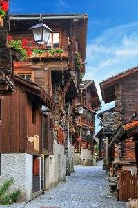 Grimentz, estrecha calle con casas de madera y flores